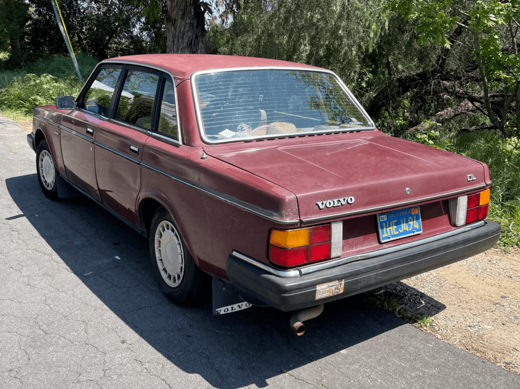 A classic maroon Volvo sedan parked on a sunny street.