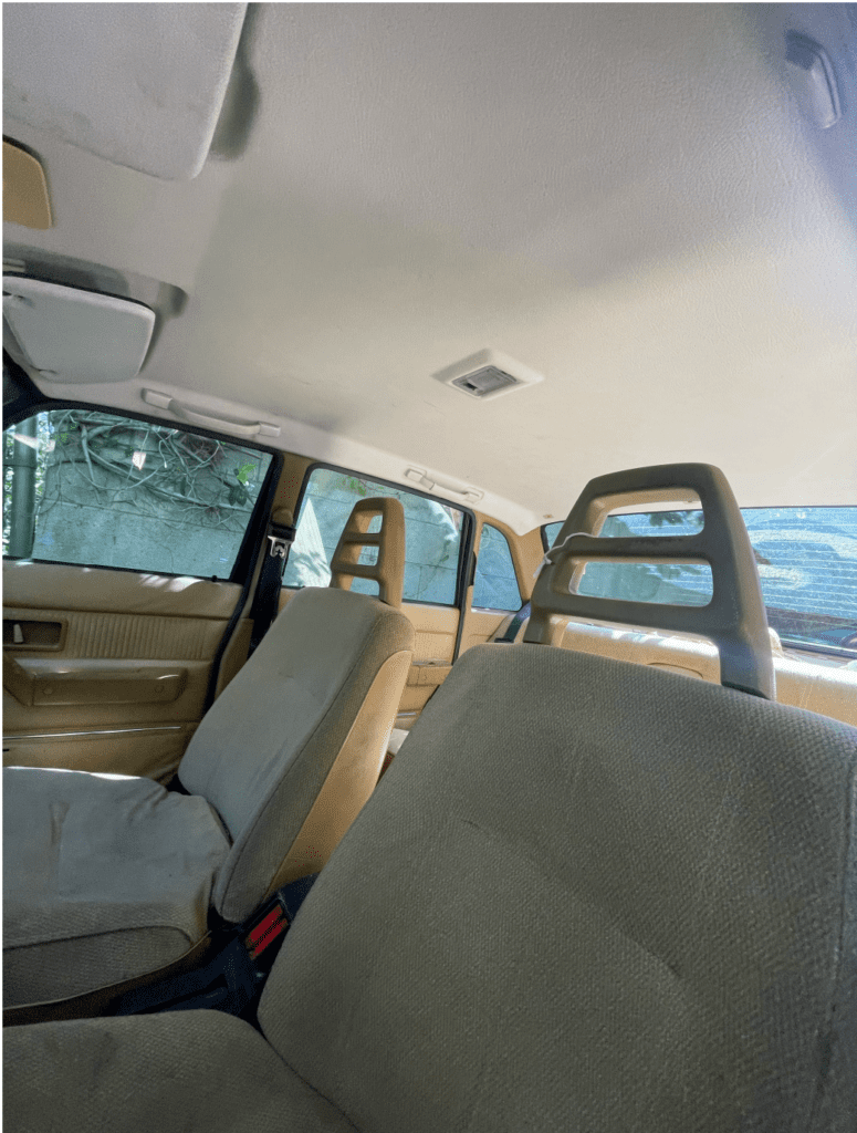 Interior view of a car showing front and back seats with beige upholstery.