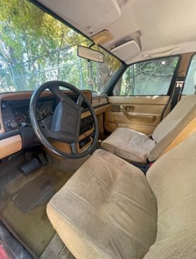 Interior view of a beige car cabin with cloth seats and steering wheel.