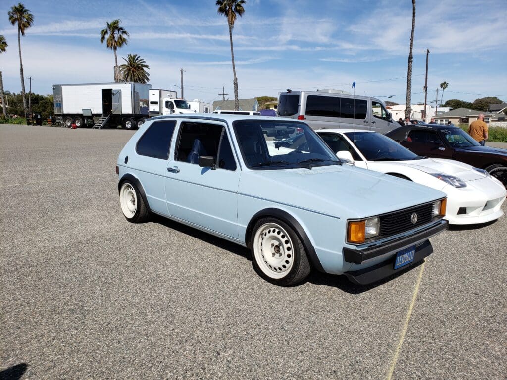 Light blue vintage hatchback car parked outdoors under clear sky.