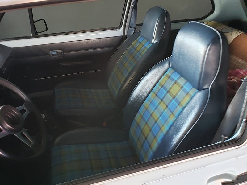 Classic car interior with blue and green plaid upholstery on seats.