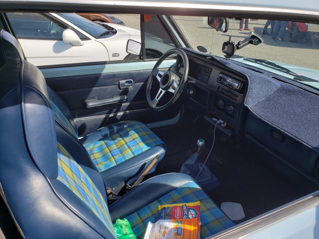Interior view of a compact car with colorful seat covers and a simple dashboard.