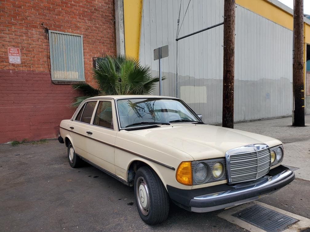 Vintage white Mercedes-Benz parked near industrial buildings.