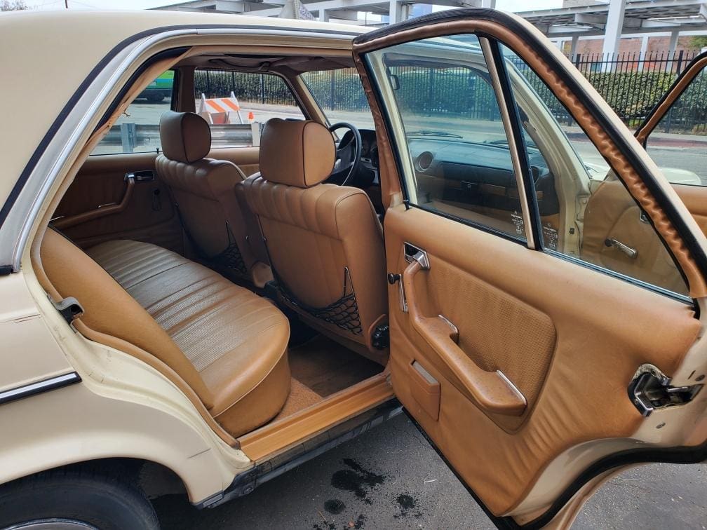 Open car door showing tan leather interior and spacious back seat.