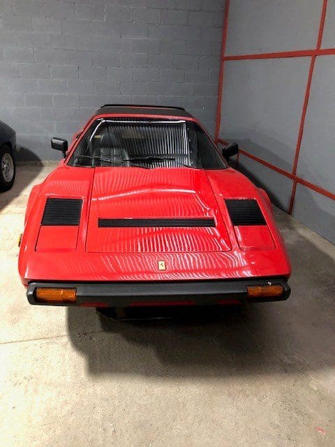 Red classic sports car parked indoors with pop-up headlights.