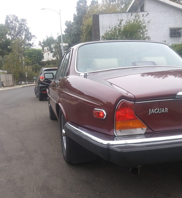 Classic maroon Jaguar parked on a residential street.