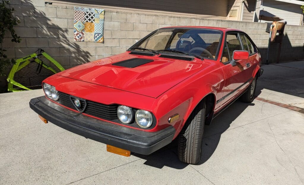 Classic red Alfa Romeo sports car parked outdoors.