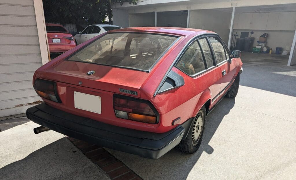 Classic red Alfa Romeo sports car parked outdoors.