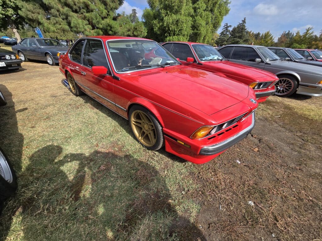 Red classic sports car parked outdoors on grass.