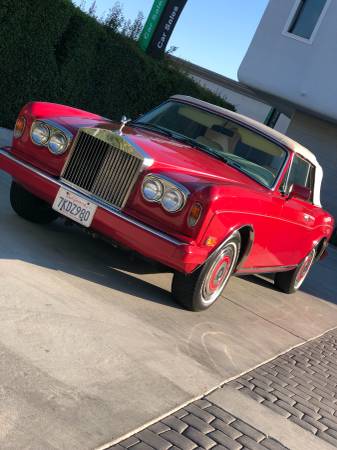 Classic red Rolls-Royce parked in sunlight.