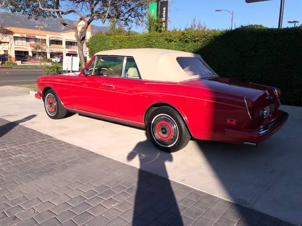 Classic red convertible car parked on a driveway in sunlight.