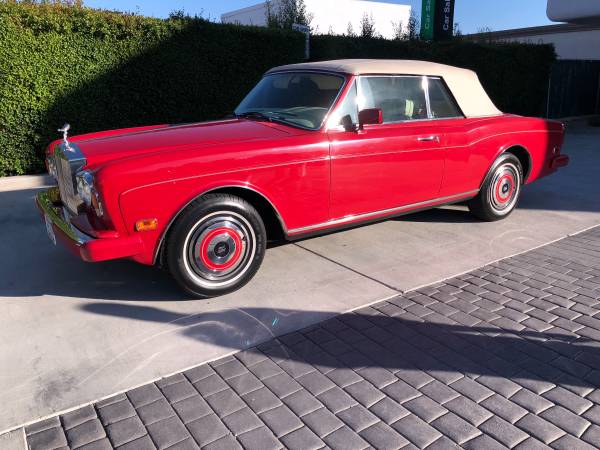 Classic red convertible car parked in a driveway on a sunny day.