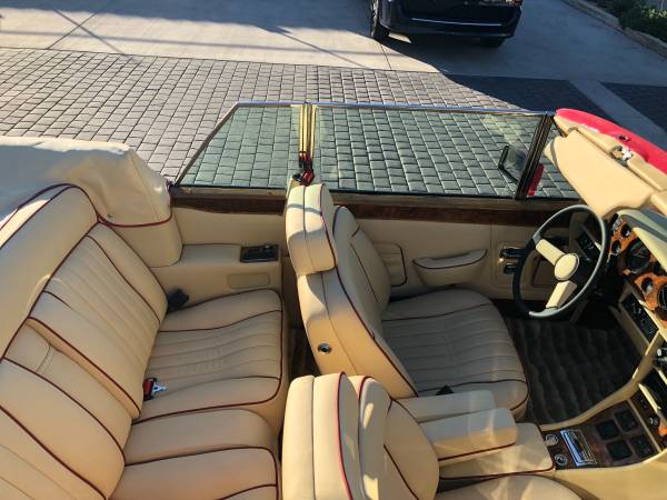Interior of a classic convertible car with beige leather seats and wooden dashboard.