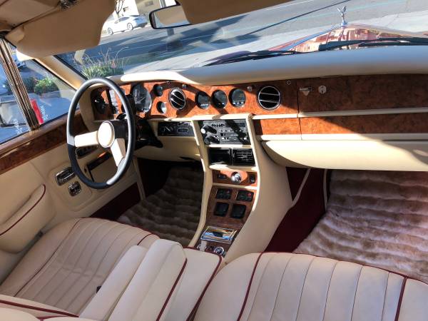 Luxurious vintage car interior with wooden dashboard and cream leather seats.