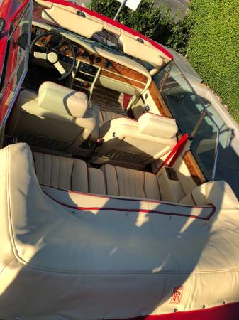 Sunlit boat interior with cushioned seating and steering wheel.