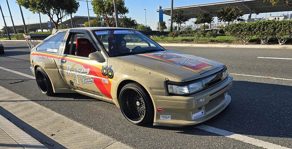 Modified gold sports car with racing decals and black rims.