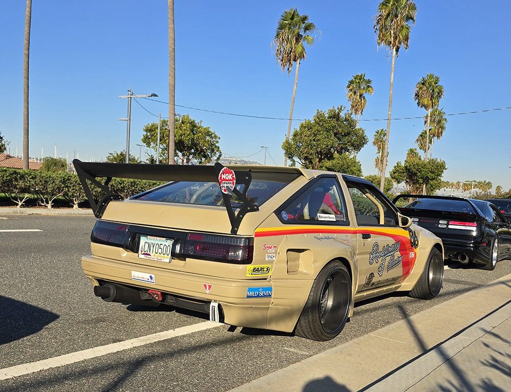 Modified gold sports car with racing decals and black rims.