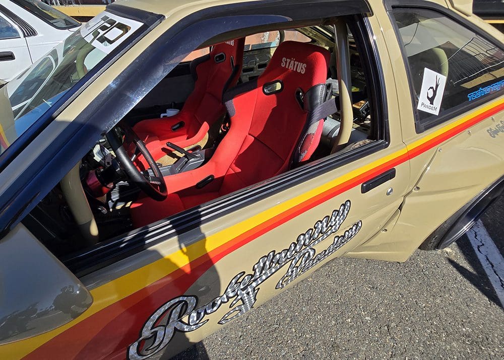 Rally car interior with red racing seats and safety harnesses.