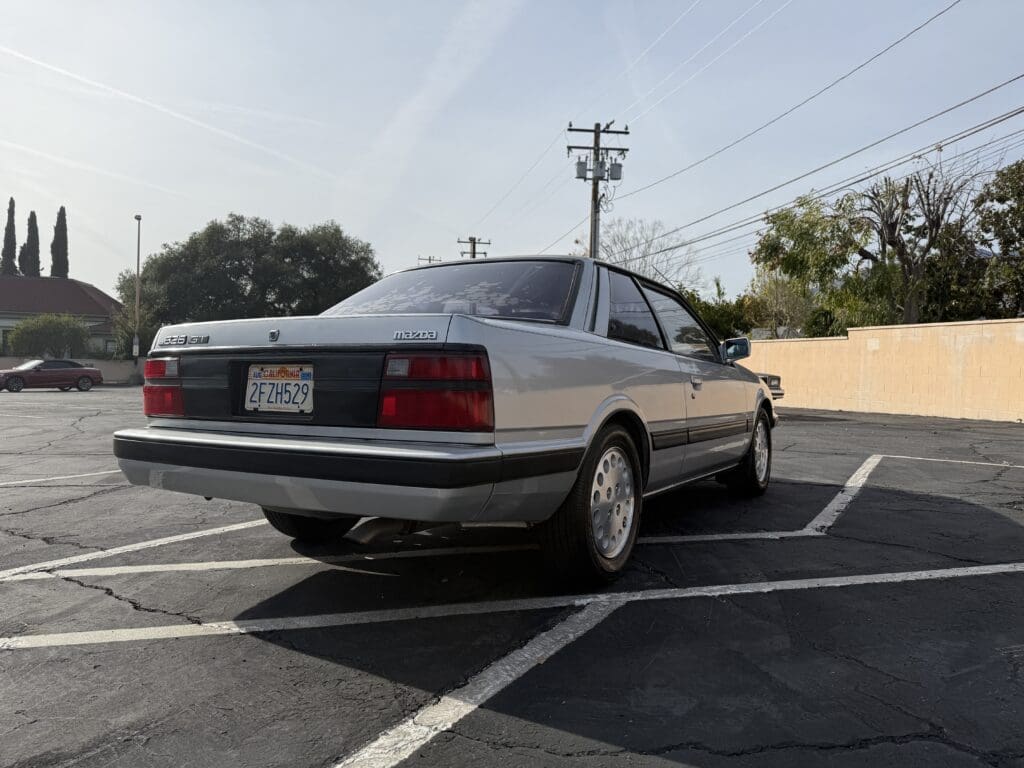 Classic silver sedan parked in a lot under clear sky.