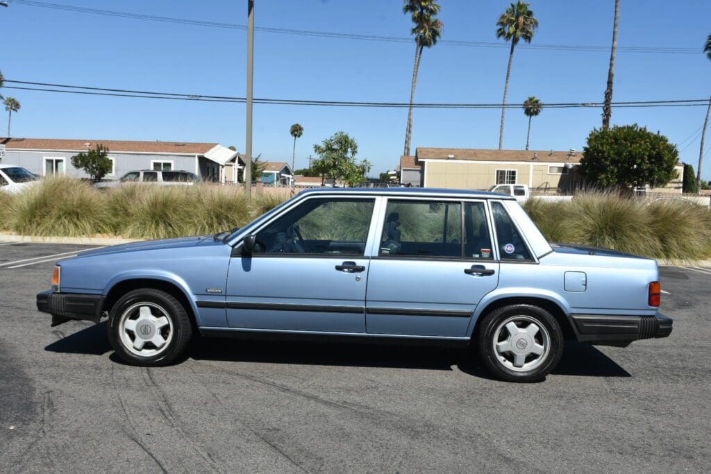Classic blue four-door sedan parked on a sunny street.