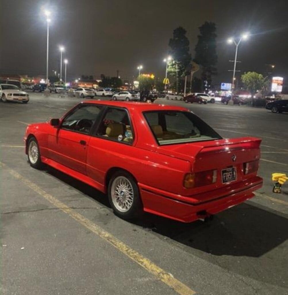 Red sports car parked in a lit parking lot at night.