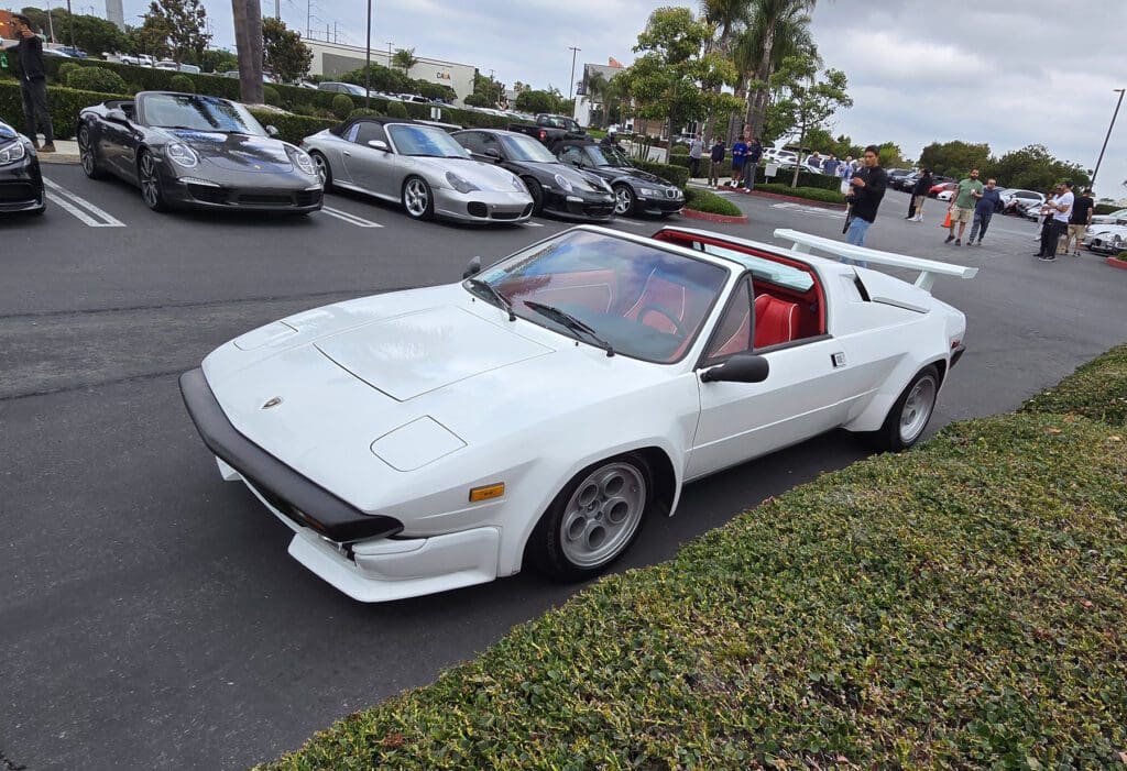 White classic sports car with red interior parked at a car meet.
