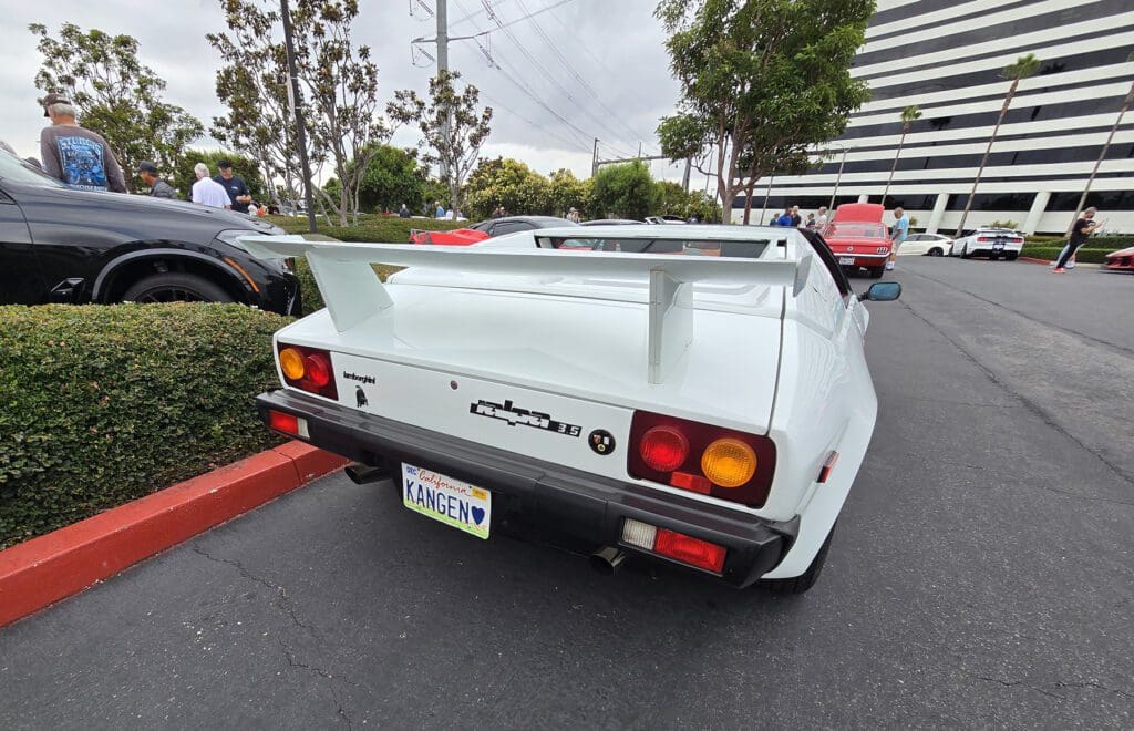 White classic sports car with red interior parked at a car meet.