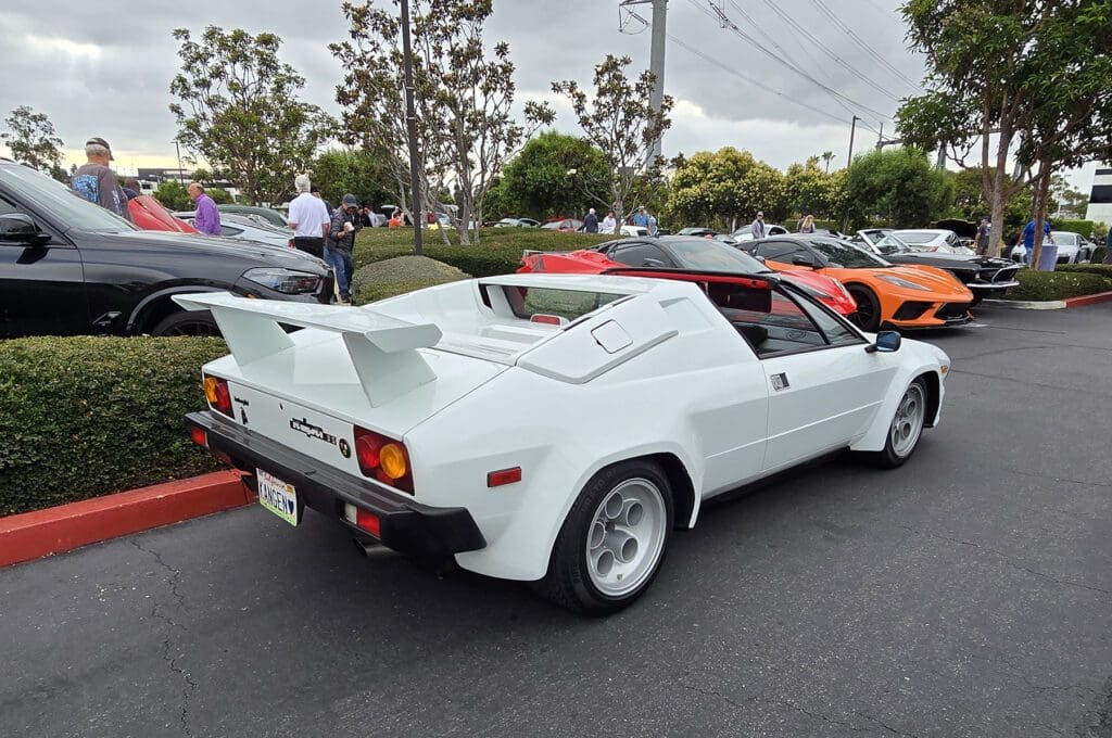 White classic sports car with red interior parked at a car meet.