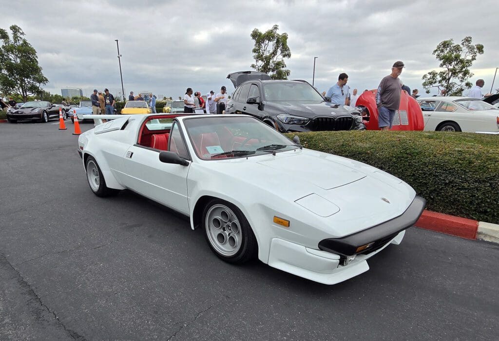 White classic sports car with red interior at a car show.