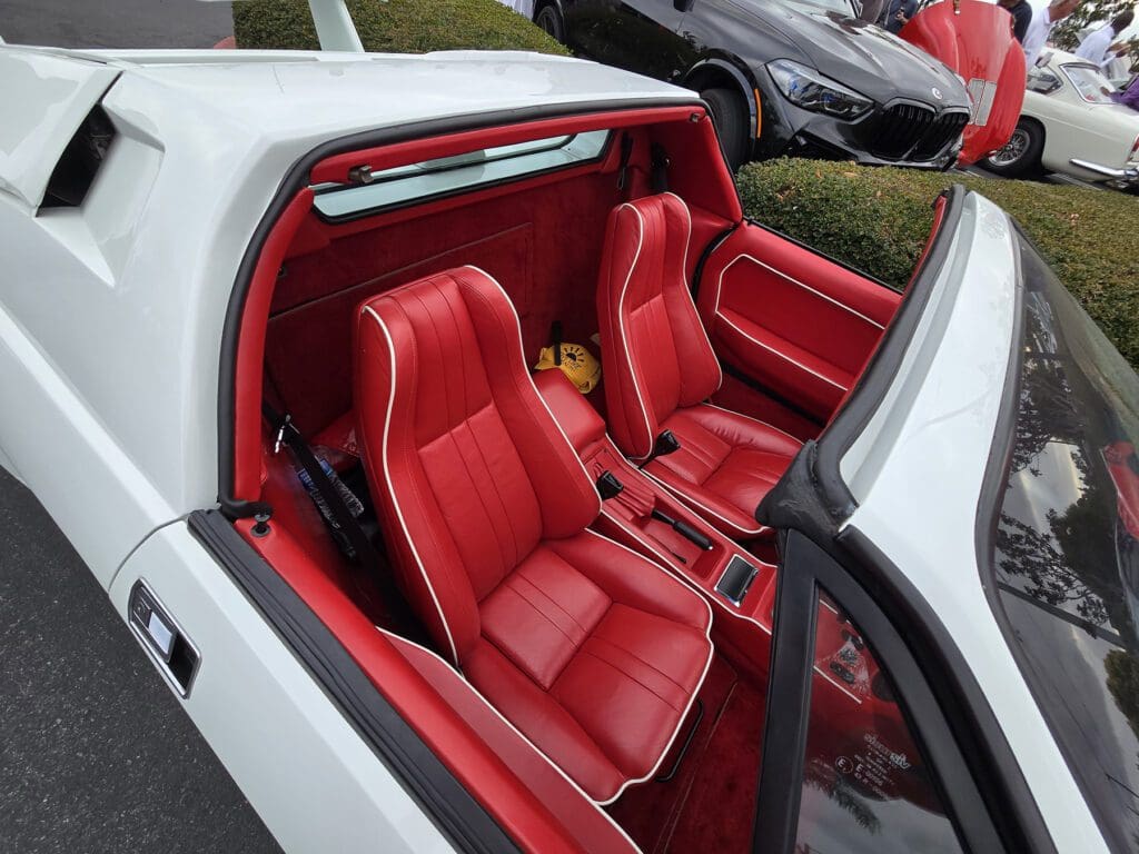 Vintage car interior with striking red leather seats and classic design.