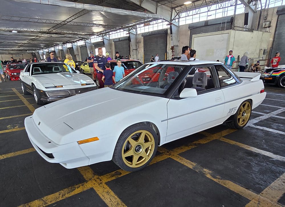 White sports car with gold rims displayed indoors.