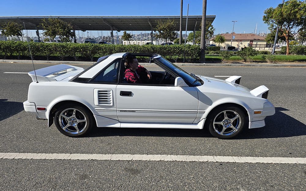 White convertible sports car parked in a lot on a sunny day.