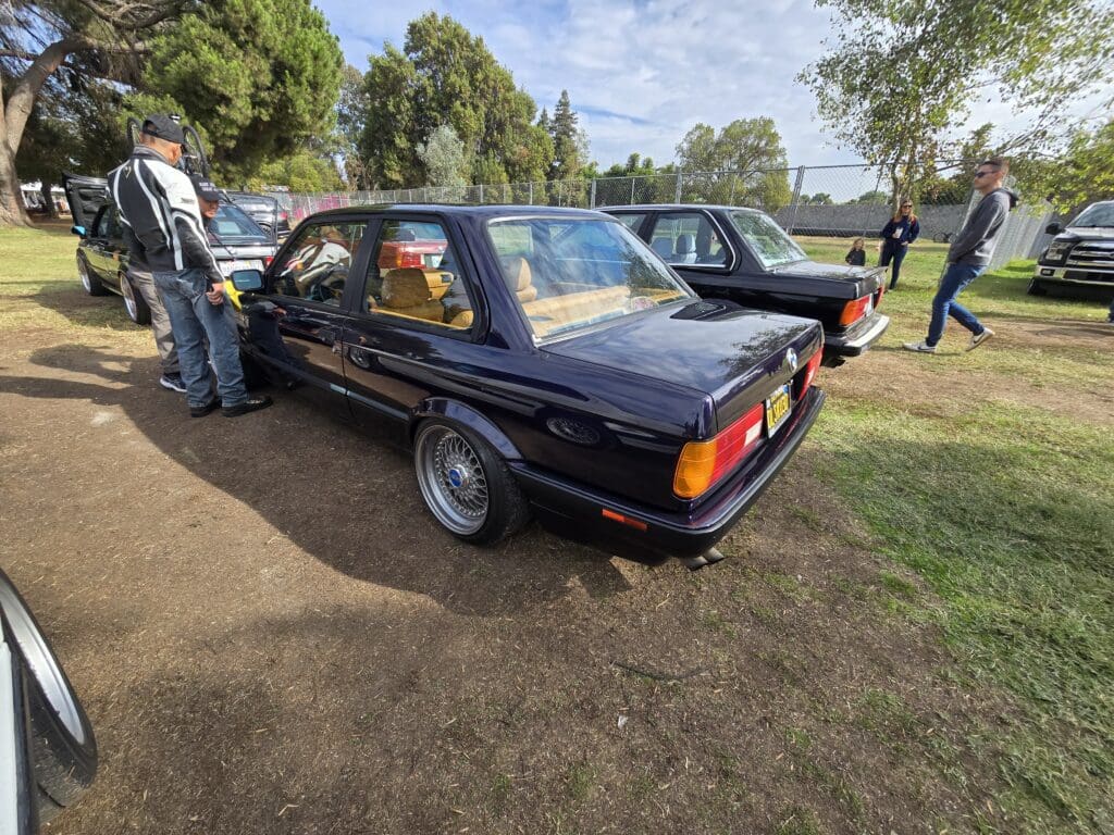 Classic black vintage car parked on grass at a car show.