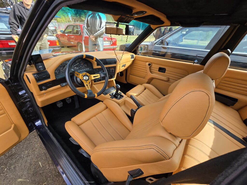 Luxurious tan leather interior of a classic car with wooden dashboard accents.