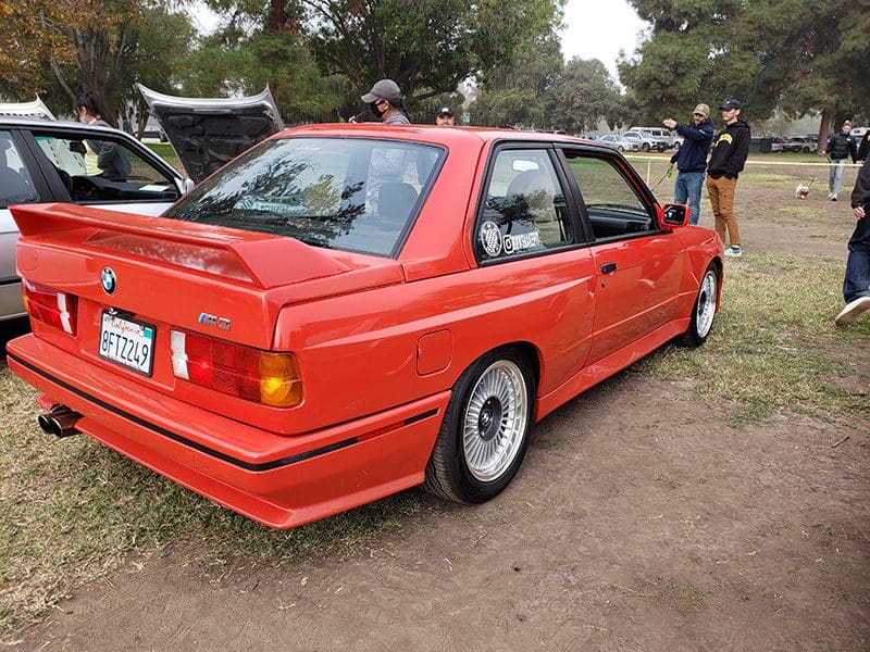 Classic red BMW sedan parked outdoors on grass.