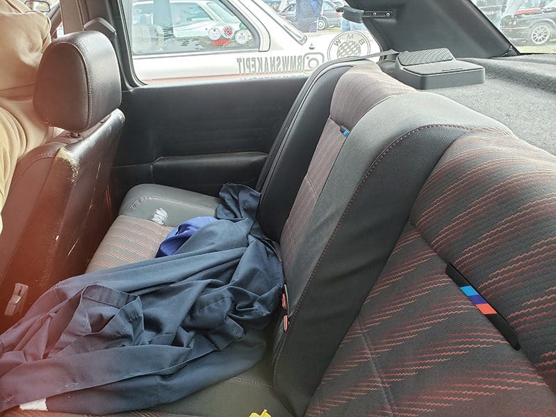 Car backseat with clothes and a water bottle scattered.