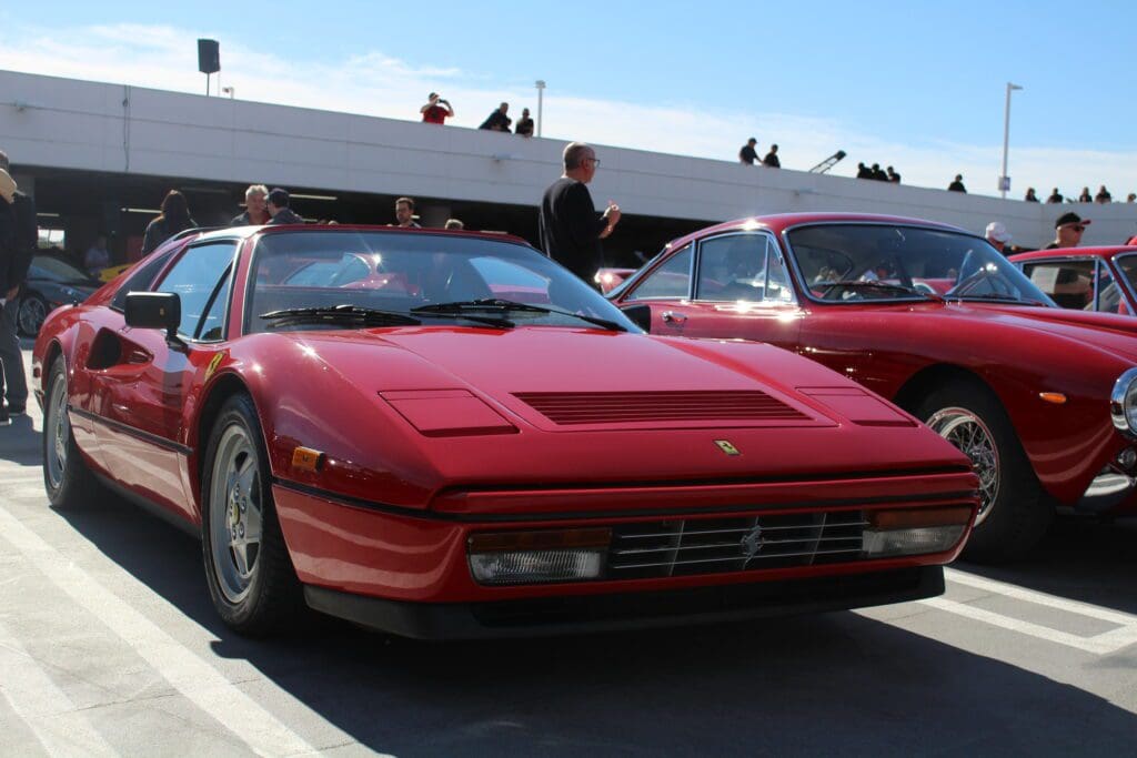 A red classic Ferrari sports car parked at an outdoor event.