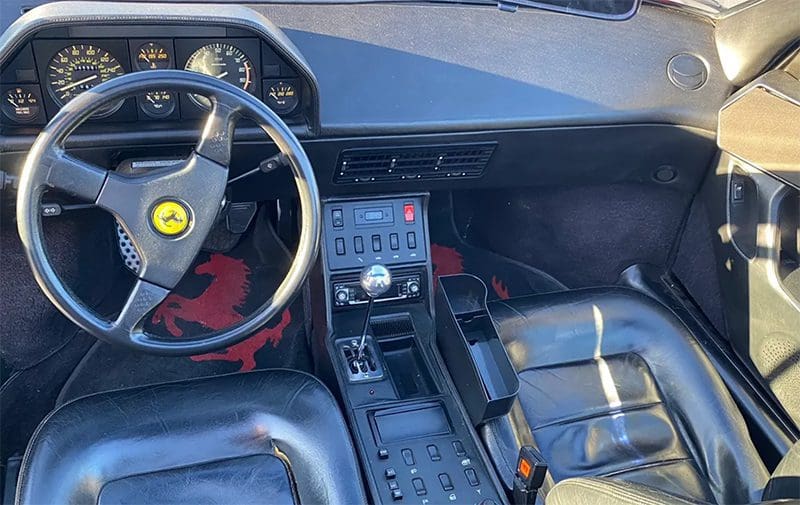 Interior of a classic Ferrari sports car with iconic steering wheel and dashboard.