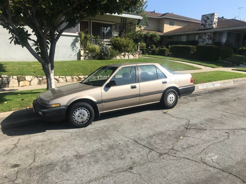 An older beige sedan parked on a residential street.