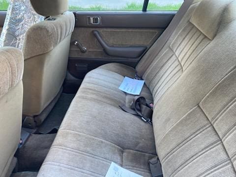 Interior of a car with beige fabric seats and papers on the back seat.