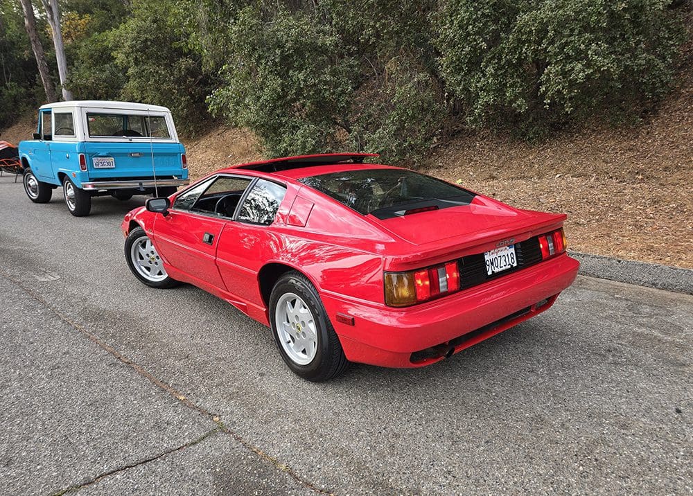 Red sports car parked on a road near greenery.