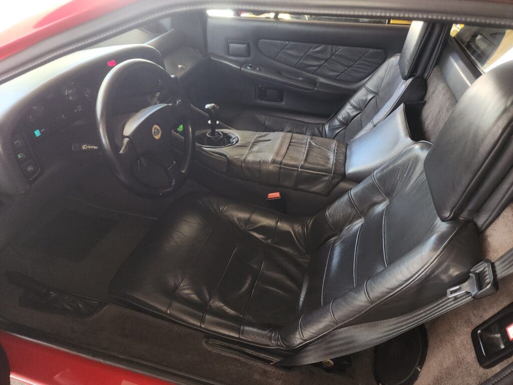 Interior of a classic car with black leather seats and a red exterior.