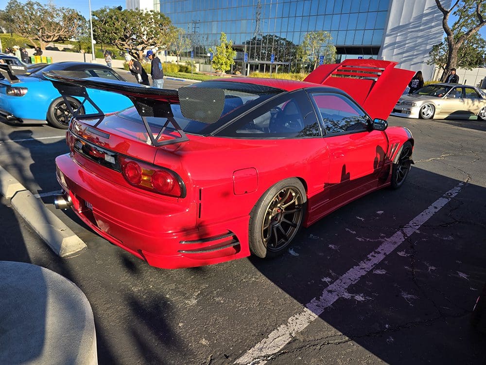 Red sports car with customized black rims parked outdoors.