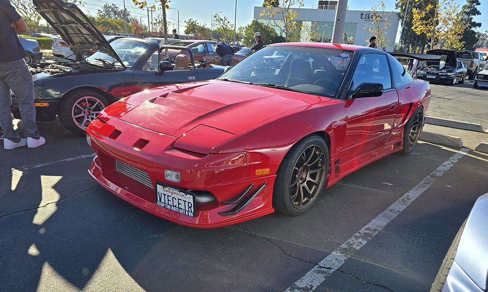 Red sports car parked in a lot on a sunny day.