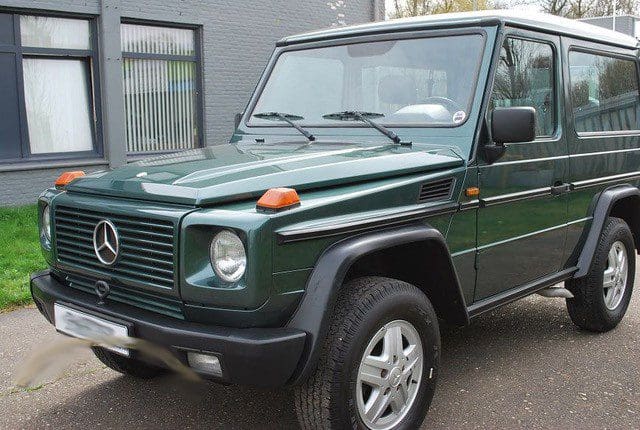 Dark green Mercedes-Benz G-Class SUV parked outside a building.