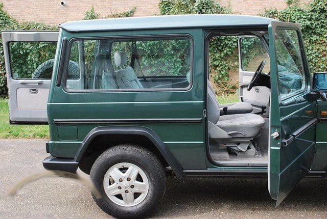Green SUV with the driver's door open showing the interior.