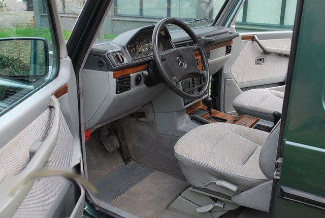 Interior of a vintage car with gray seats and wooden dashboard accents.
