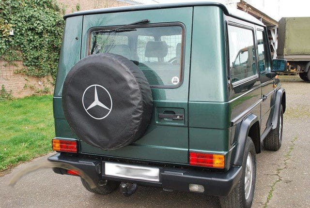 Rear view of a green Mercedes-Benz G-Class with a spare tire cover.