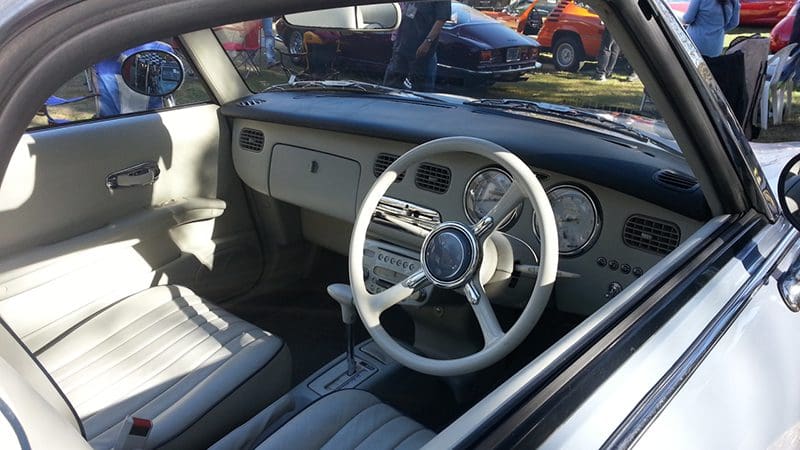 Interior of a vintage car with a classic steering wheel and dashboard.