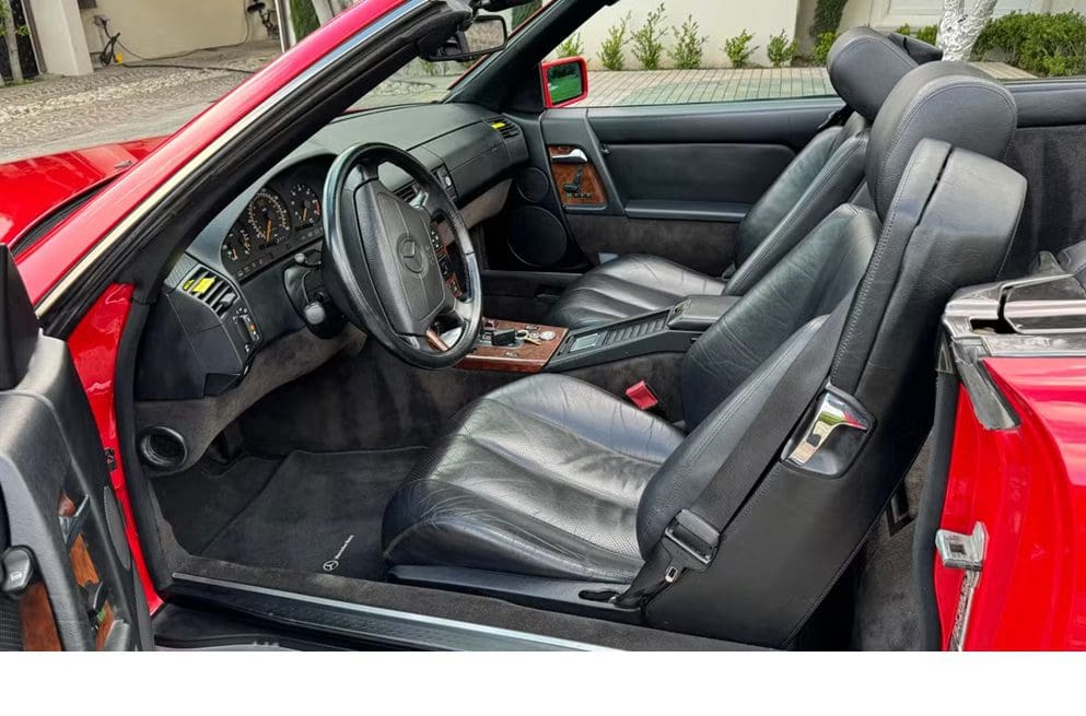 Interior of a classic car with black leather seats and a simple dashboard.